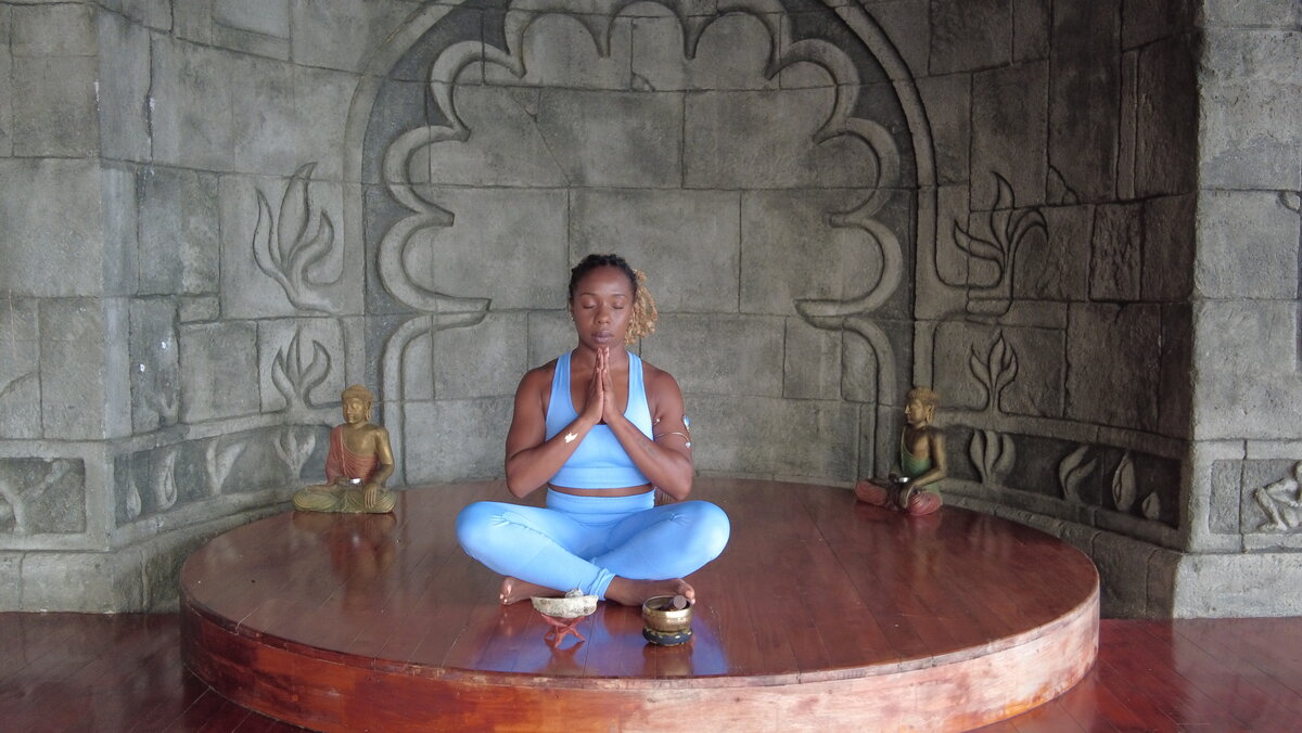 Jessica in seated meditation pose, hands in prayer