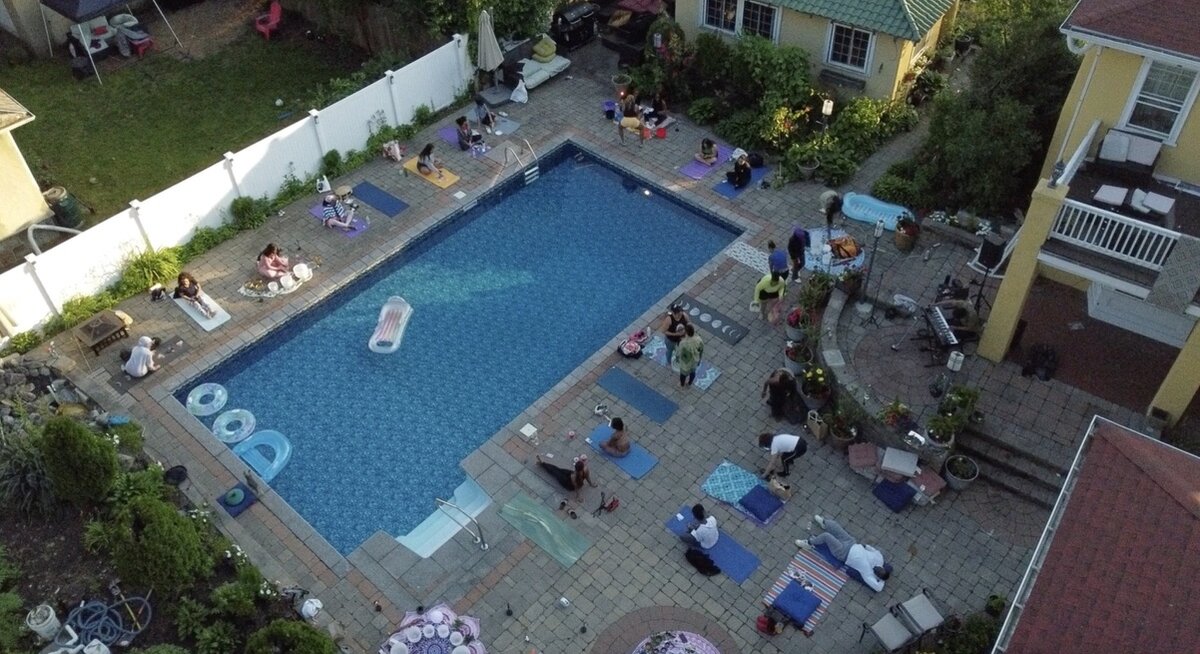 Aerial view of a poolside yoga class, participants on mats around the pool